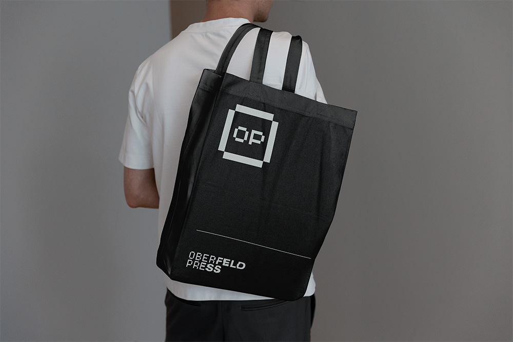 Oberfeld Press reusable book bag with white OP logo.